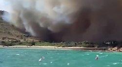 Inferno in spiaggia, le fiamme minacciano i turisti: bagnanti in fuga e soccorsi in mare, cosa sta succedendo